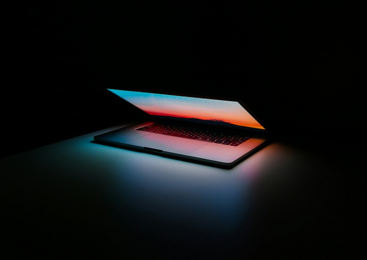 A laptop glowing with abstract colorful light in a dark room